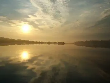 Sunset reflecting on a calm lake with clouds.