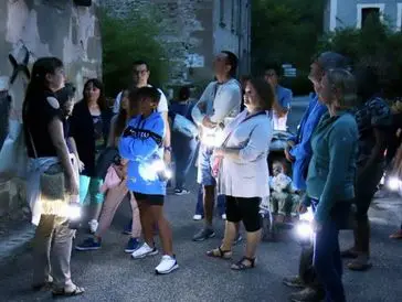 Group of people exploring outdoors at night with flashlights.