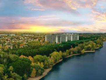 Sunset over a city park with a river and high-rise buildings.