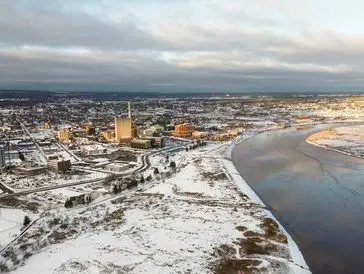Snow-covered town along a river under a cloudy sky.