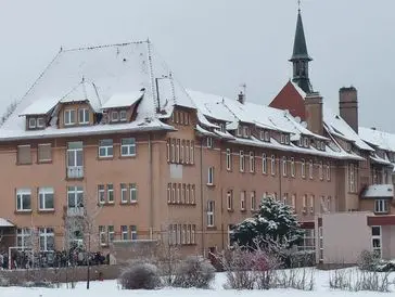 Snow-covered building with a tall church spire in the background.