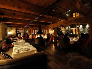 Cozy rustic restaurant with warmly lit wooden interiors and diners enjoying meals.