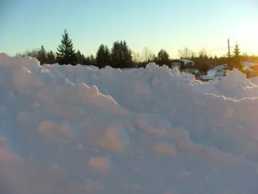 A large pile of snow outdoors during sunset.