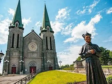 A historic church with twin spires and a statue in the foreground.