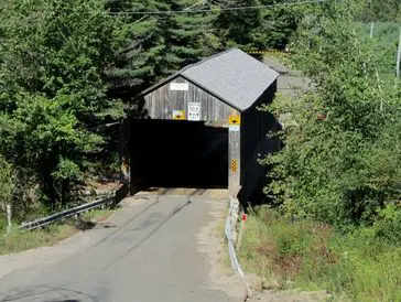 A wooden covered bridge surrounded by trees.