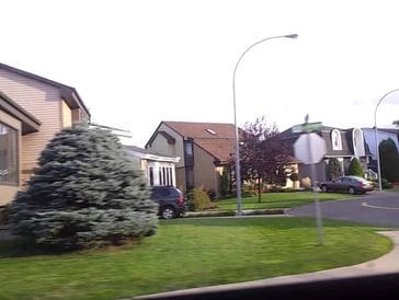 Suburban street with houses and green lawns on a clear day.
