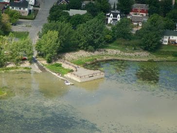 Aerial view of a small dock and boats near a tree-lined shoreline.