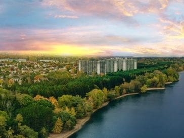 Sunset over a city park with a river and high-rise buildings.