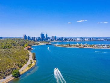 Aerial view of a city skyline by a river with boats.