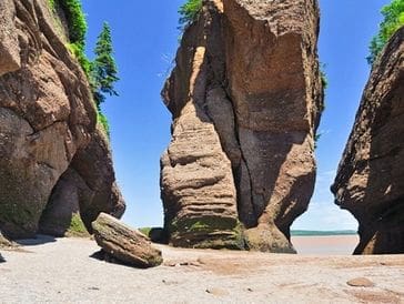 Unique rock formations on a sandy beach under a clear blue sky.