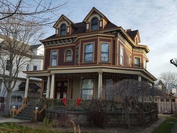 A large Victorian-style house with a wraparound porch and intricate woodwork.