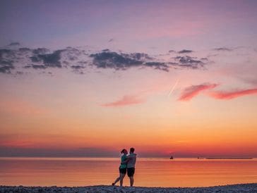 Couple hugging at sunset by the beach.