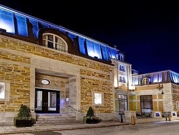 Elegant stone building illuminated at night with blue roof lighting.