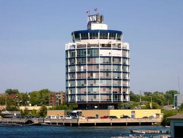 Round building labeled 'INN' by the water under clear sky.