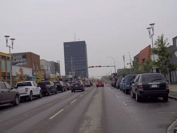 Busy city street lined with parked cars and traffic.