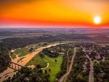 A vibrant sunset over a winding river and green landscape.
