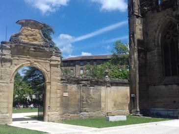 Historic stone wall and arch under a blue sky with scattered clouds.