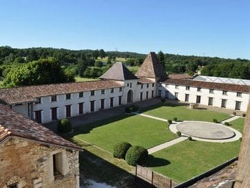 Historic castle courtyard with green lawns and stone buildings.
