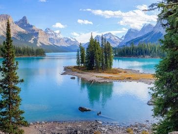 Serene lake with small island and distant snow-capped mountains.