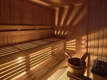 Warm wooden sauna interior with sunlight casting striped shadows.