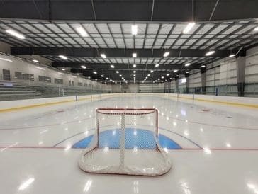 Empty ice hockey rink with a goal net in the foreground.