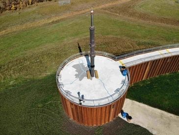 A tall rocket model displayed on a circular platform outdoors.