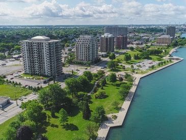 A waterfront park with green lawns and tall buildings in the background.