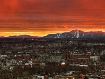 Sunset over a city with mountains in the background.