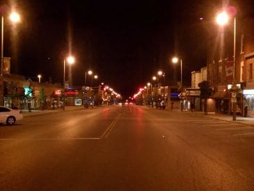 Empty city street at night illuminated by streetlights.