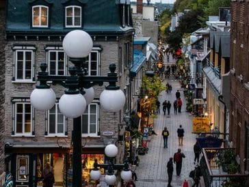 Evening street scene with people walking along a charming cobblestone road.