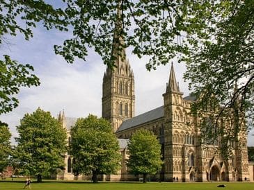 Historic stone cathedral surrounded by trees under a clear sky.