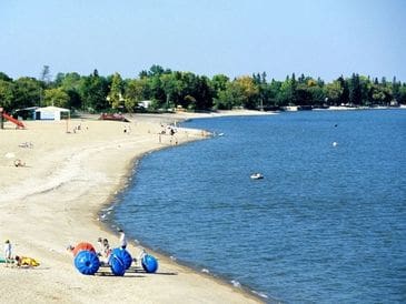 Calm beach with blue water balls and people enjoying the sunny day.