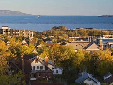Scenic view of a coastal town with houses and greenery under a clear sky.