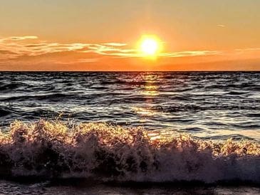 Sunset over ocean waves with vibrant colors.