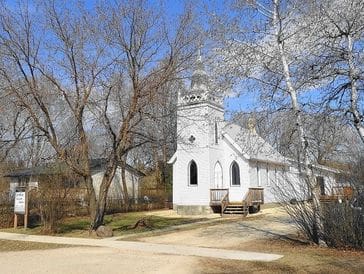 White church surrounded by trees and clear sky.
