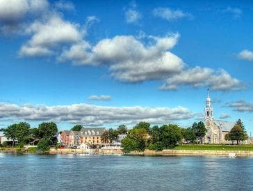 Scenic view of a riverside town with historic buildings under a blue sky.