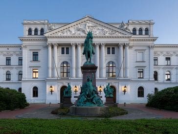 Statue in front of a grand neoclassical building at dusk.