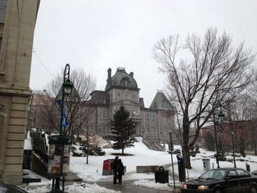 Historic castle-like building in snowy winter setting with bare trees.
