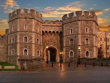 Historic castle entrance with round towers at sunset.