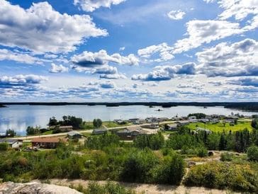 Scenic view of a river under a partly cloudy sky with greenery in the foreground.