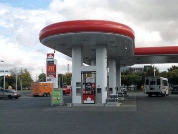 A retro gas station canopy with a red roof and white pillars.