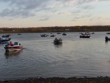 Boats floating on calm water under a cloudy sky at dusk.