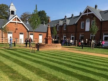 Well-maintained lawn with striped patterns in front of historic brick buildings.