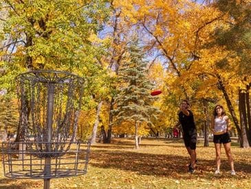 Person playing disc golf in a colorful autumn park.