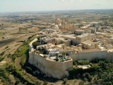 A fortified historic city atop a rocky hill surrounded by arid landscape.