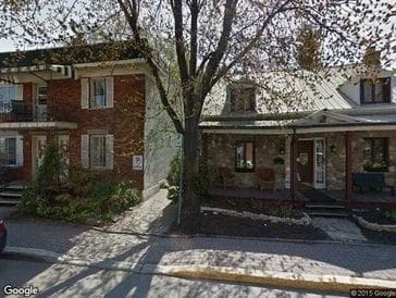 Two residential houses with a tree and driveway between them.