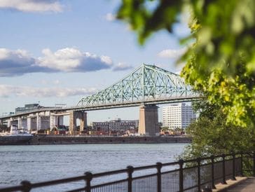 A large steel bridge over a river on a partly cloudy day.