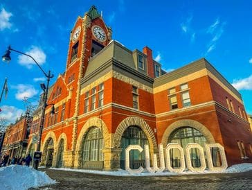 Historic red brick clock tower building under a bright blue sky.
