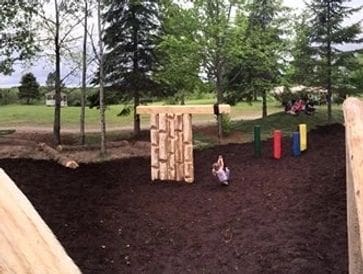A child playing near wooden climbing structures in a park.
