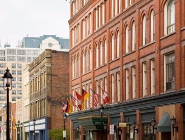 Historic brick buildings with flags lining a city street.